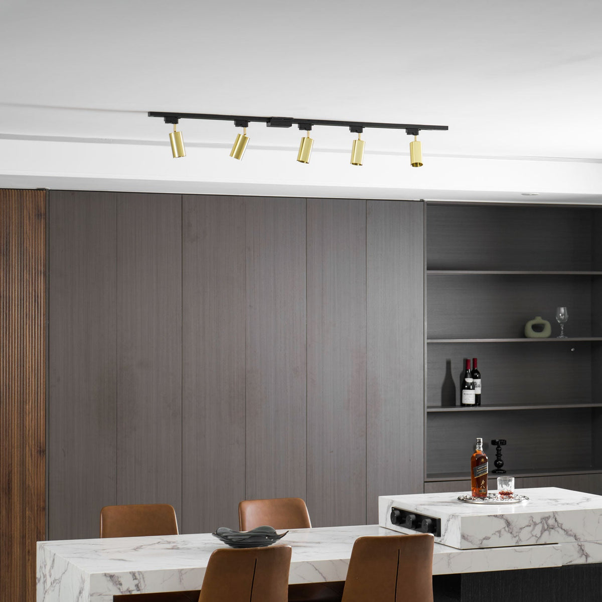 Five gold Clérachic spotlights on a black track, above a dark panelled wall with open shelves and a marble table.
