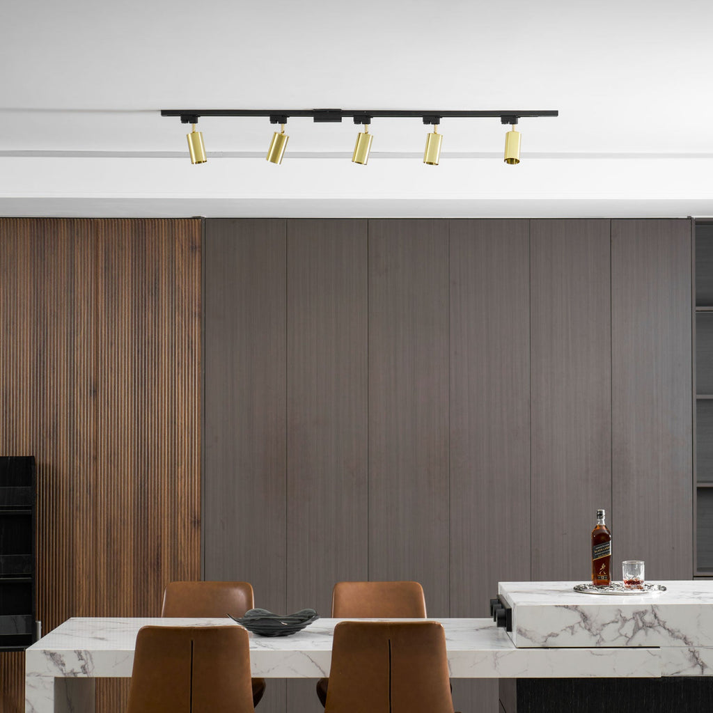 Clérachic track with five gold heads above a dining room with grey panelling, a bottle of whisky and brown chairs.