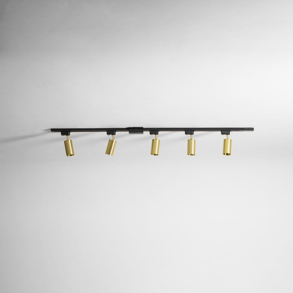 Clérachic black track with five gold cylindrical spotlights, seen along a plain white ceiling.