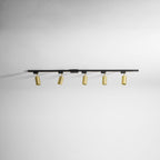 Clérachic black track with five gold cylindrical spotlights, seen along a plain white ceiling.
