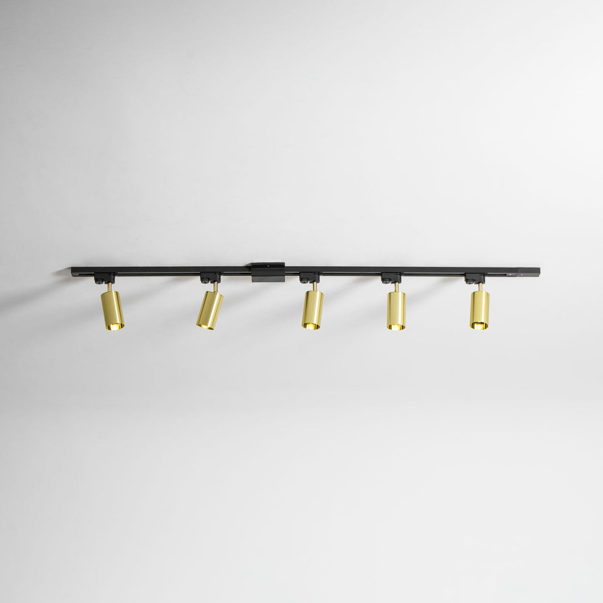 Clérachic black track with five gold spotlight heads, shown on a white ceiling with each head turned slightly.