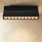 Clérachic elongated black grille spotlight bar with multiple honeycomb cells, mounted flush against a ceiling rail.