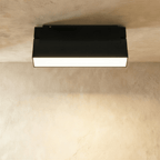 Clérachic black surface-mount linear floodlight glowing along its frosted lens, fixed to an overhead track rail.