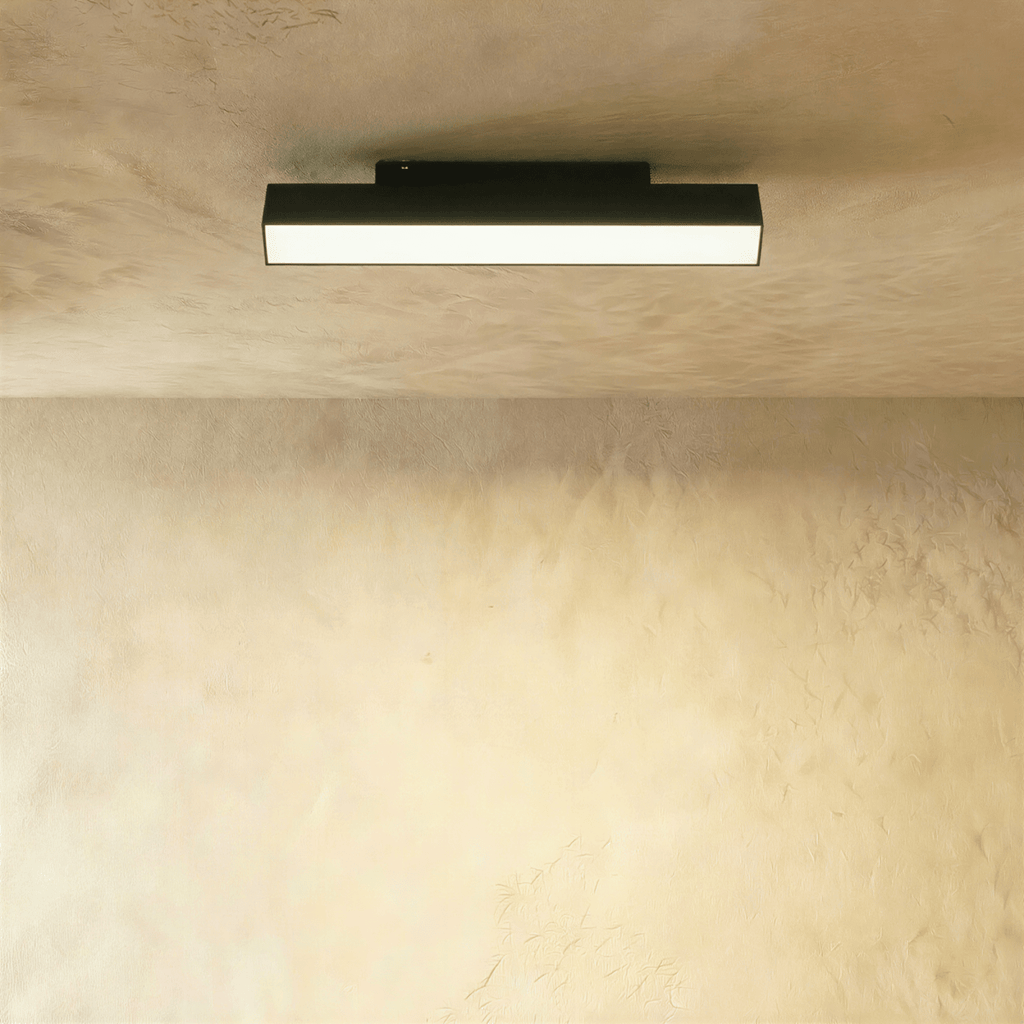 Clérachic elongated black linear floodlight bar with a bright frosted diffuser, mounted along a ceiling track rail.