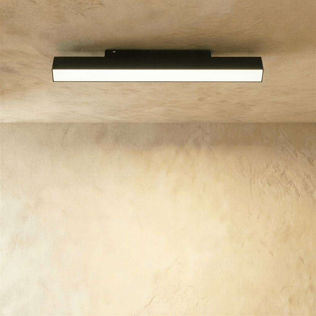 Clérachic long black linear track floodlight casting even light from its frosted strip beneath a plaster ceiling.