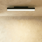 Clérachic long black linear track floodlight casting even light from its frosted strip beneath a plaster ceiling.