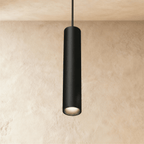 Clérachic slim black cylindrical pendant lamp hanging from a track rail on a cord, glowing warm at its open end.