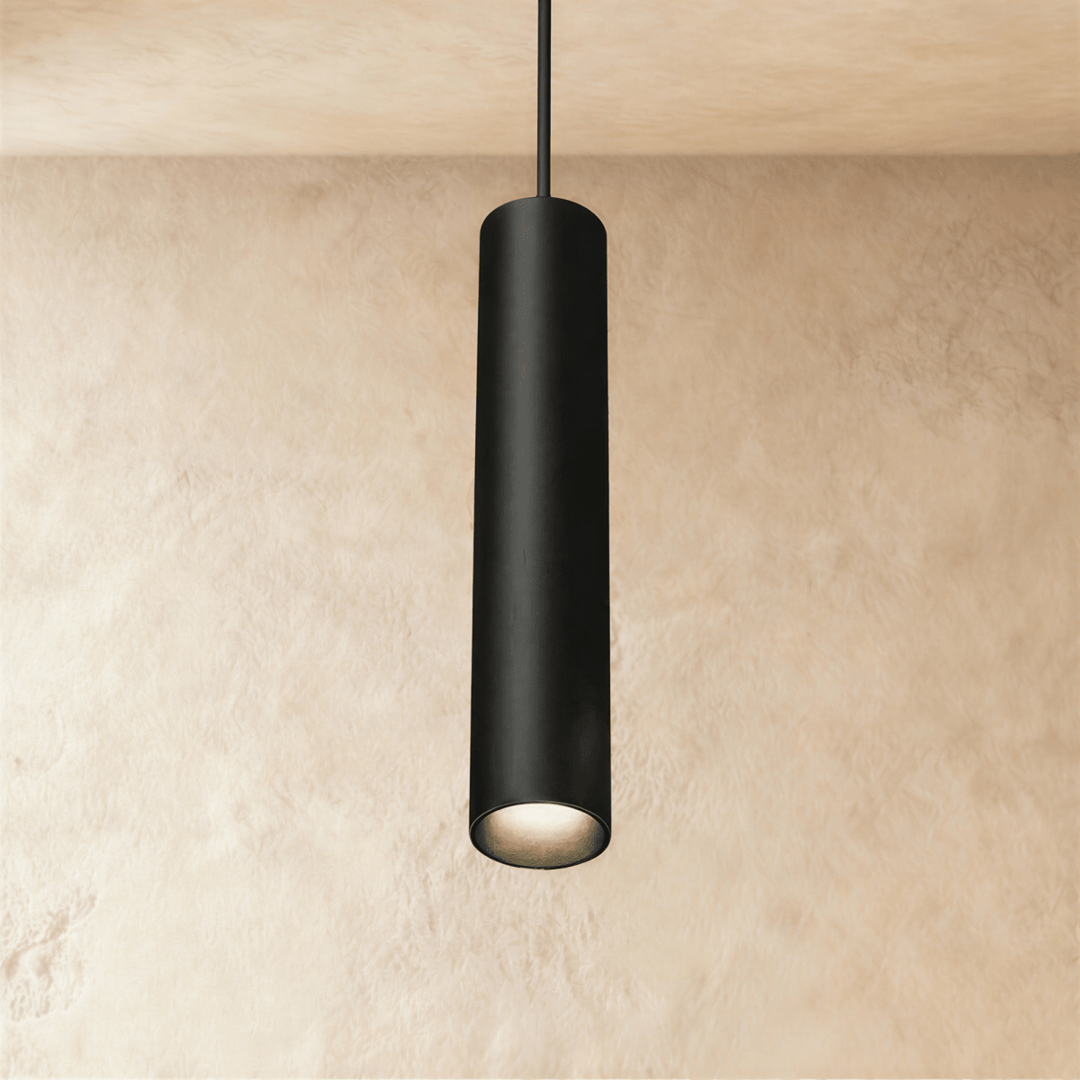 Clérachic slim black cylindrical pendant lamp hanging from a track rail on a cord, glowing warm at its open end.