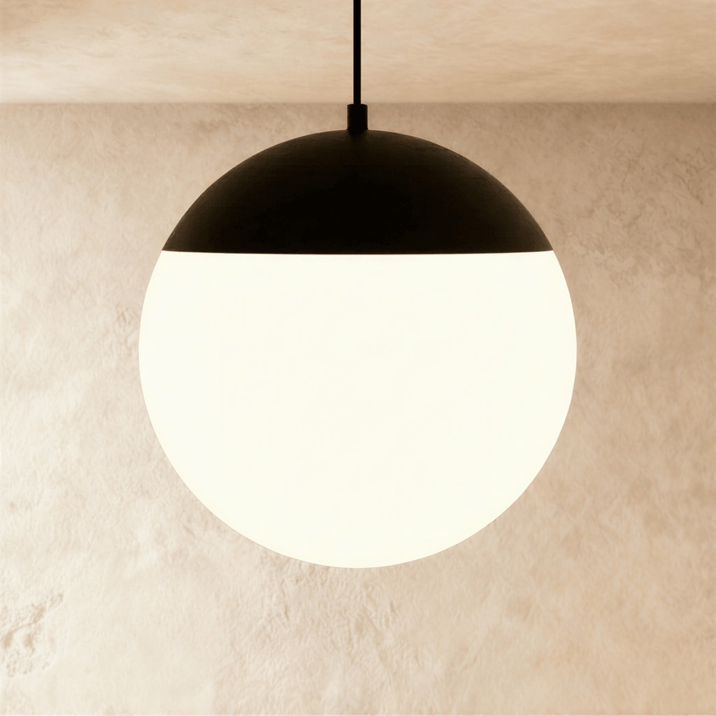 Clérachic black and white globe pendant lamp suspended on a cord from a ceiling track, glowing softly inside.