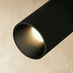 Clérachic close-up of a black track spotlight's interior lens, showing the warm LED glow inside its round bezel.