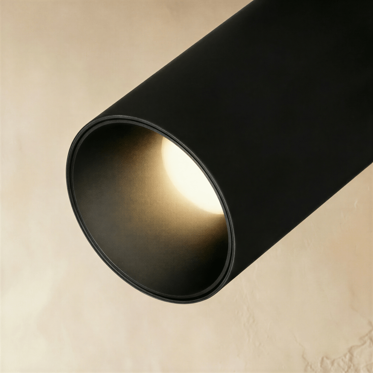 Clérachic close-up of a black track spotlight's interior lens, showing the warm LED glow inside its round bezel.