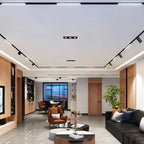 Clérachic black track lighting run along a living room ceiling, illuminating a bookshelf, sofa and dining nook.