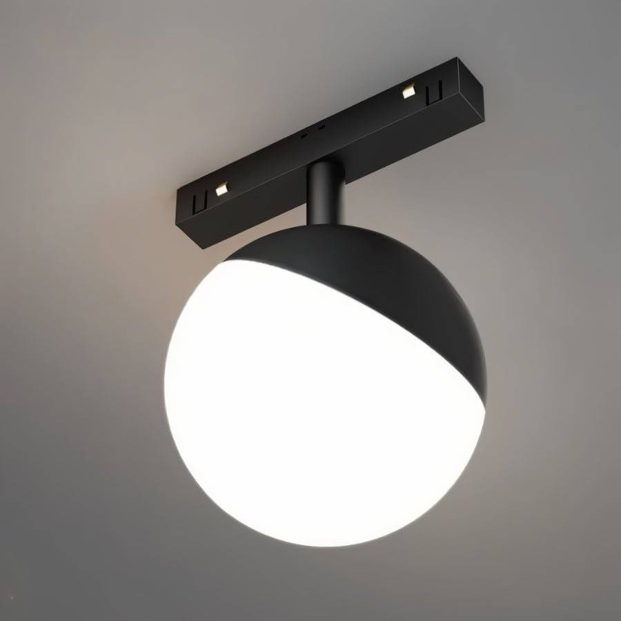 Clérachic black and white globe track lamp shown close against a grey backdrop, its lower half glowing bright.