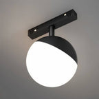 Clérachic black and white globe track lamp shown close against a grey backdrop, its lower half glowing bright.