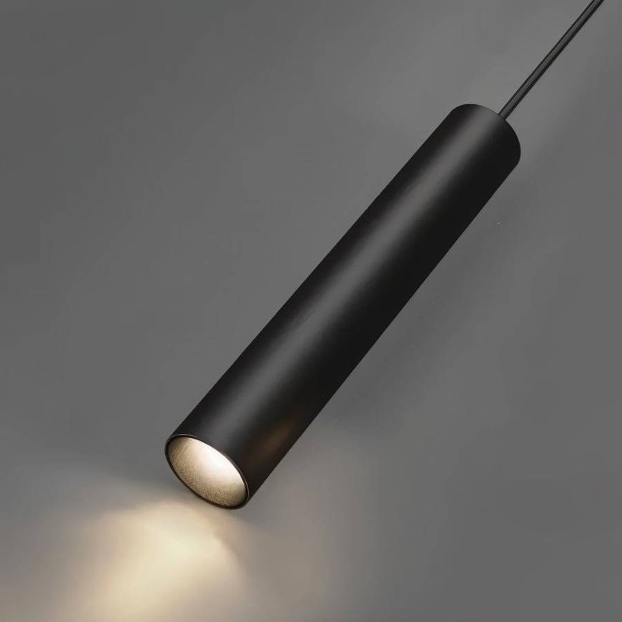 Clérachic black cylindrical pendant lamp on its cord, photographed close against grey with a warm glow at its tip.