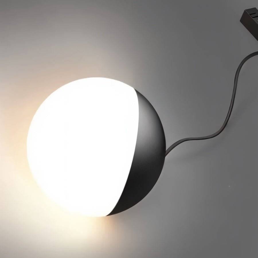 Clérachic black and white globe lamp with its connecting cord, shown close against grey, glowing softly.