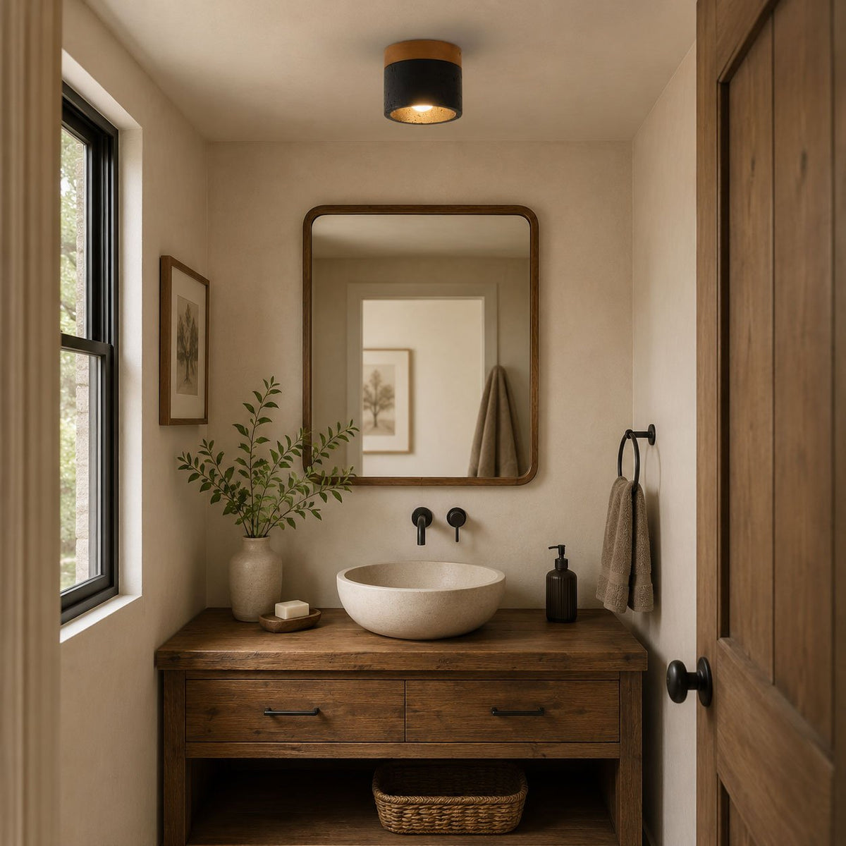 Above a rustic wood washstand with a stone basin and a framed mirror, a Clérachic flush ceiling light glows warm in a small cloakroom.
