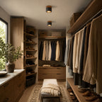 In a walk-in wardrobe lined with wood shelving and hanging knitwear, two Clérachic flush ceiling lights glow overhead.