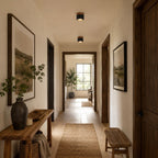 Along a long hallway with a jute runner and framed landscapes, two Clérachic flush ceiling lights glow in a row.