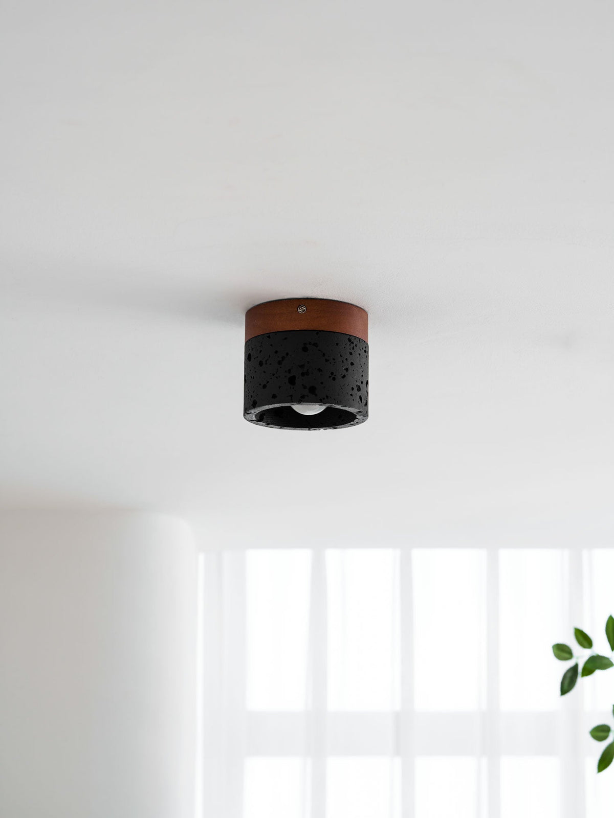 This Clérachic flush ceiling light in a pale room, switched off, with sheer curtains and a leafy sprig below.