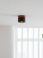 Far view of a Clérachic flush ceiling light, lit with a gold-lined inside, over a bright window with sheer curtains.
