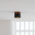 A Clérachic flush ceiling light on a white ceiling, glowing warm gold above a window with soft curtains.