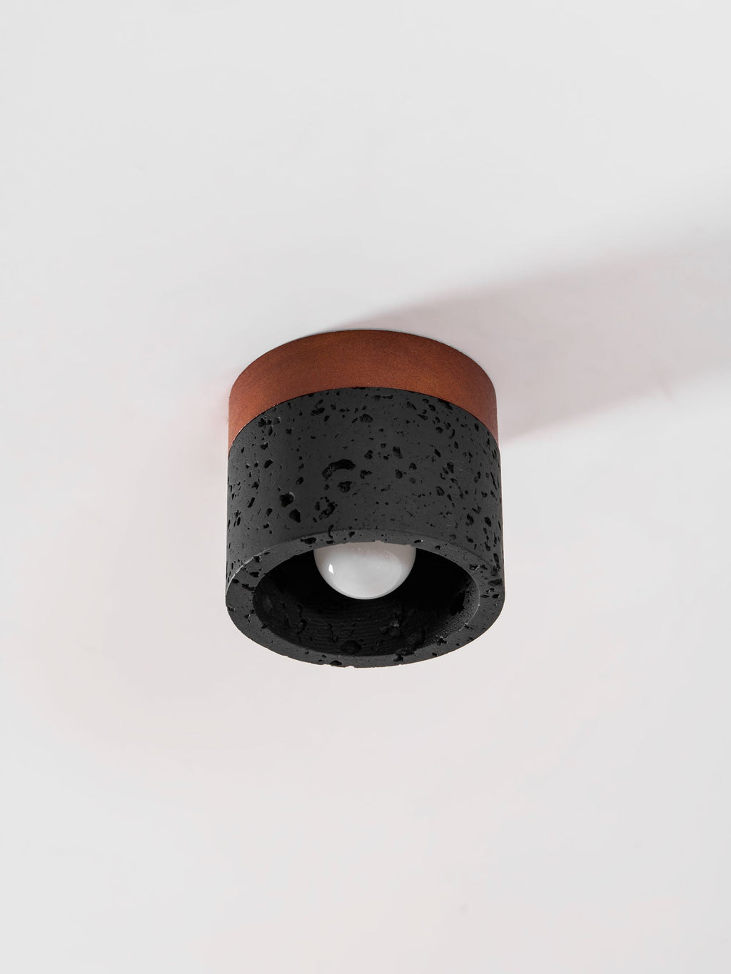 Seen from the side and below, this Clérachic flush ceiling light shows an unlit bulb in a dark stone shade.