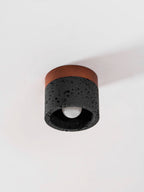 Seen from the side and below, this Clérachic flush ceiling light shows an unlit bulb in a dark stone shade.
