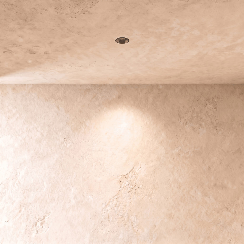 Clérachic trimless downlight set flush in a plaster ceiling, throwing a soft pool of light down a limewashed wall.