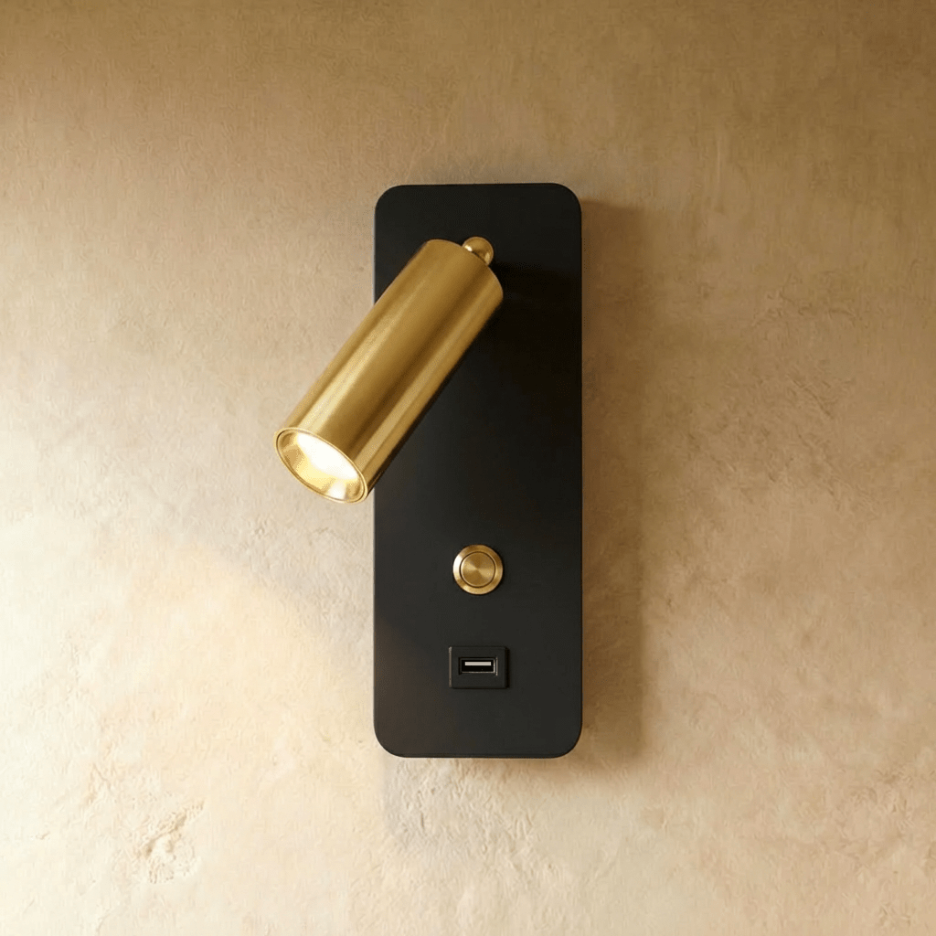A brass-toned spotlight head on a black backplate makes up this reading light variant, shown lit in this Clérachic hero shot.