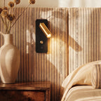 A closer crop shows the brass-and-black reading light glowing beside a stoneware jug of dried flowers, Clérachic lifestyle shot.