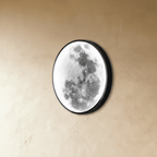 Clérachic moon wall lamp shown unlit from an angle, its grey lunar surface art visible beneath the curved glass.