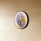 Clérachic illuminated Earth wall lamp in blue, green and cream tones, angled against a plaster wall.