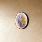 Clérachic illuminated Earth wall lamp glowing softly in blue and green, mounted at an angle on a plaster wall.