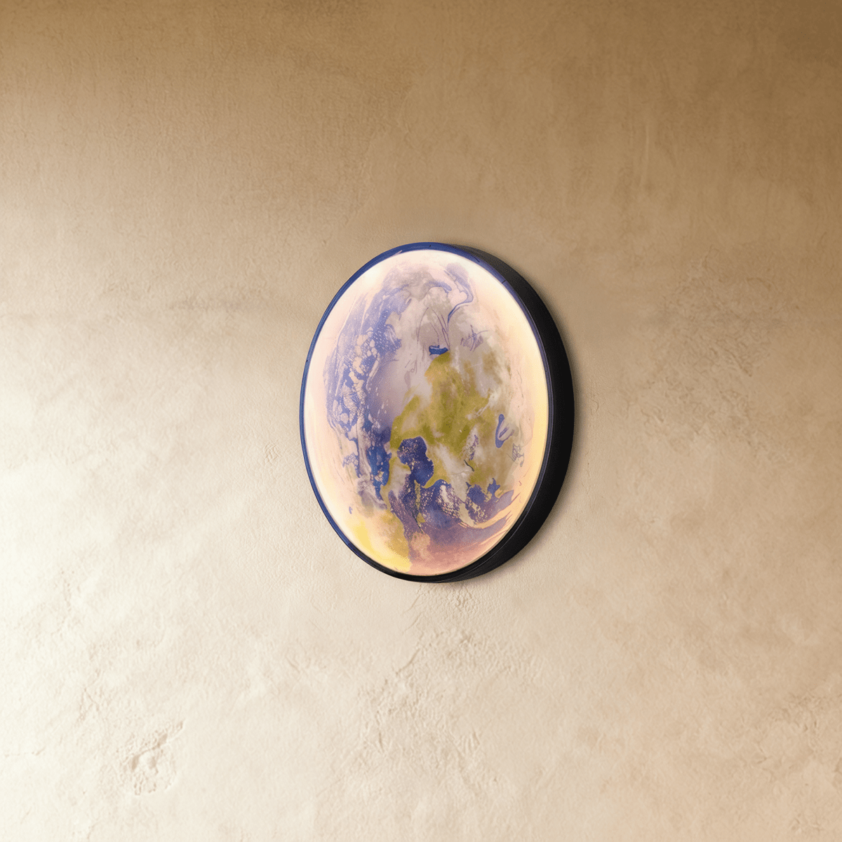 Clérachic illuminated Earth wall lamp glowing softly in blue and green, mounted at an angle on a plaster wall.