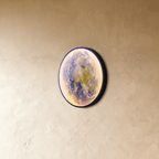 Clérachic illuminated Earth wall lamp in blue-green tones, its curved glass catching the light at an angle.