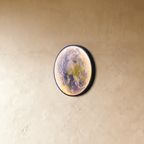 Clérachic illuminated Earth wall lamp glowing in soft blue and green, viewed from a side angle against plaster.