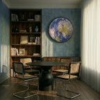 Clérachic illuminated Earth wall lamp mounted on a blue wall above a sideboard in a dining room with cane chairs.