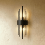 Clérachic black metal wall sconce with radiating fluted glass rods and a curved backplate glowing warm against plaster.