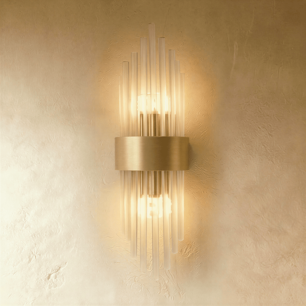 Clérachic brass wall sconce with fluted glass rods radiating from a rectangular gold-tone backplate against plaster.