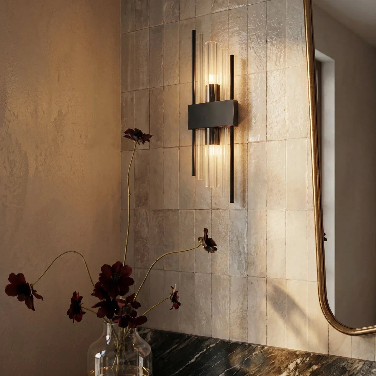 Clérachic black metal wall sconce mounted on tiled bathroom wall, its fluted glass rods glowing beside a mirror.