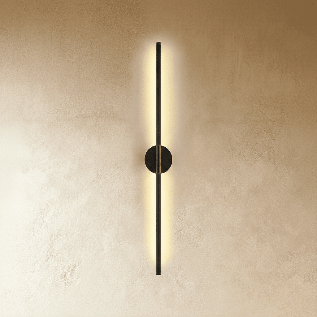 Clérachic black slim wall light glows along its full length, round canopy centred on a warm plaster wall.