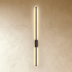 Clérachic black slim wall light glows top to bottom, its oval canopy set midway on a plaster wall.