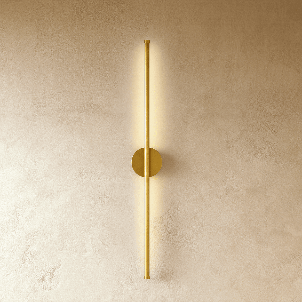 Clérachic brushed gold slim wall light glows along its full length, round canopy on a warm plaster wall.