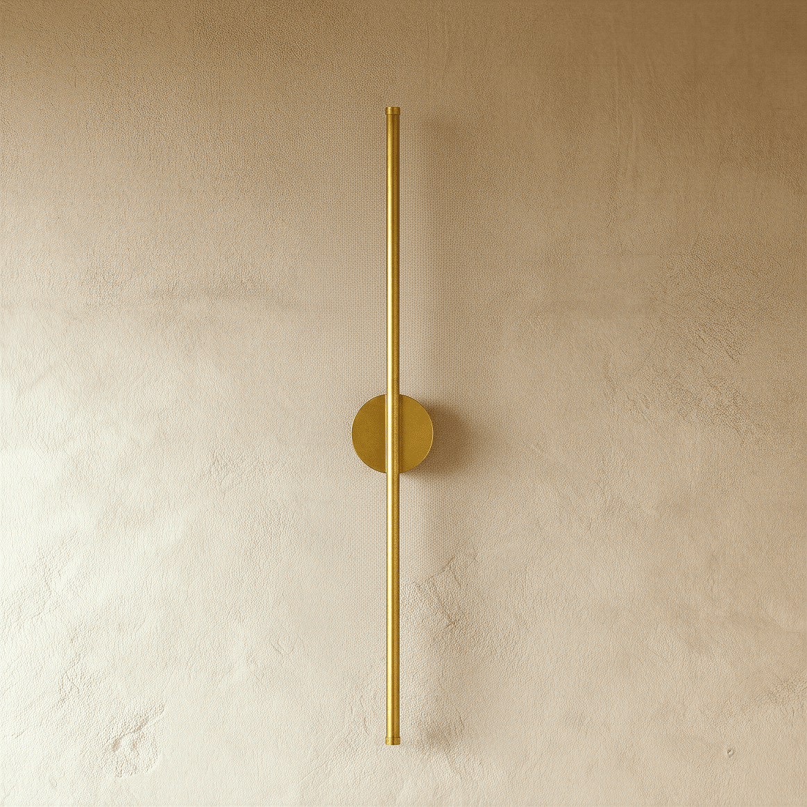 Clérachic brushed gold slim wall light shown unlit, a thin rod fixed by a round canopy to a plaster wall.