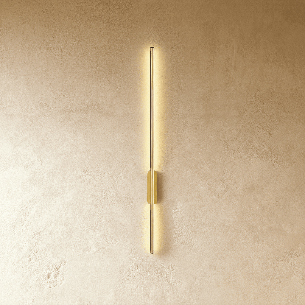 Clérachic brushed gold slim wall light glows top to bottom, its oval canopy set midway on a plaster wall.