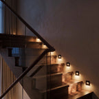At night, the black recessed step lights glow warm along the same walnut staircase treads, Clérachic lifestyle shot.