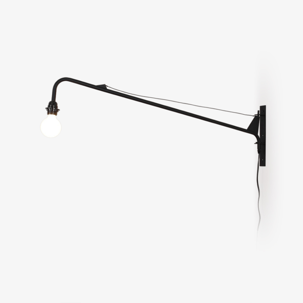 Black swing-arm wall light from Clérachic on a white wall, with a braced arm, a round white globe bulb and a trailing cord.