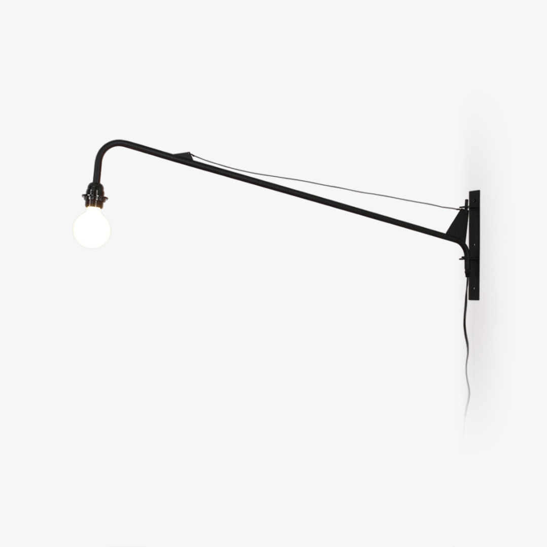 Black swing-arm wall light from Clérachic on a white wall, with a braced arm, a round white globe bulb and a trailing cord.