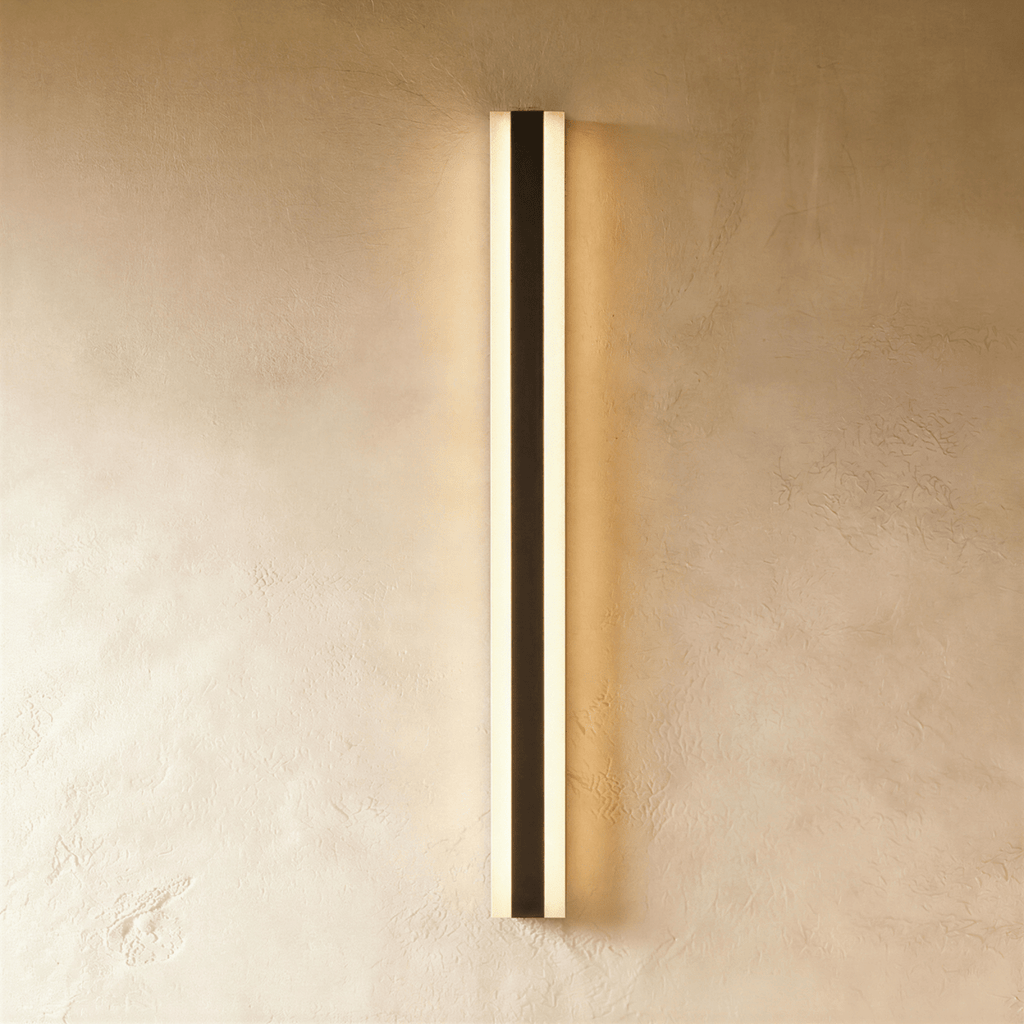 The black aluminium column sconce is shown lit against a softly textured plaster wall in this Clérachic hero shot.